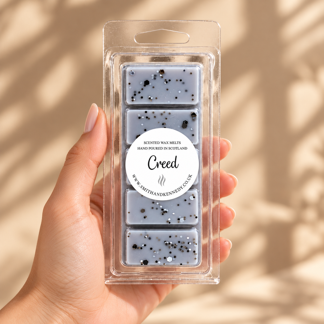 Creed wax melt snap bar held in a hand against a warm neutral background