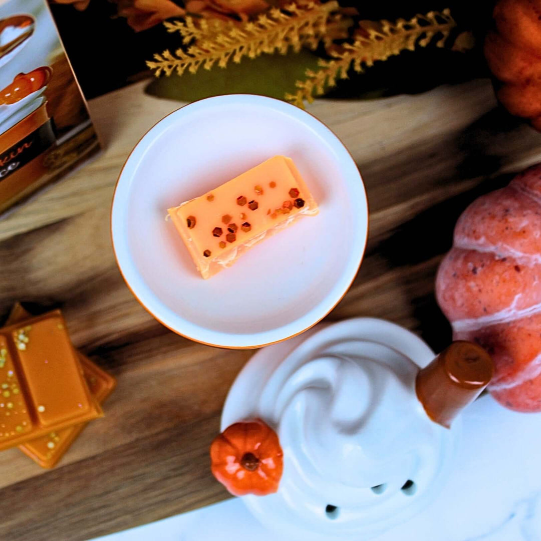 Pumpkin Spice Latte ceramic wax melt burner with sculpted lid, surrounded by pumpkins and autumn leaves