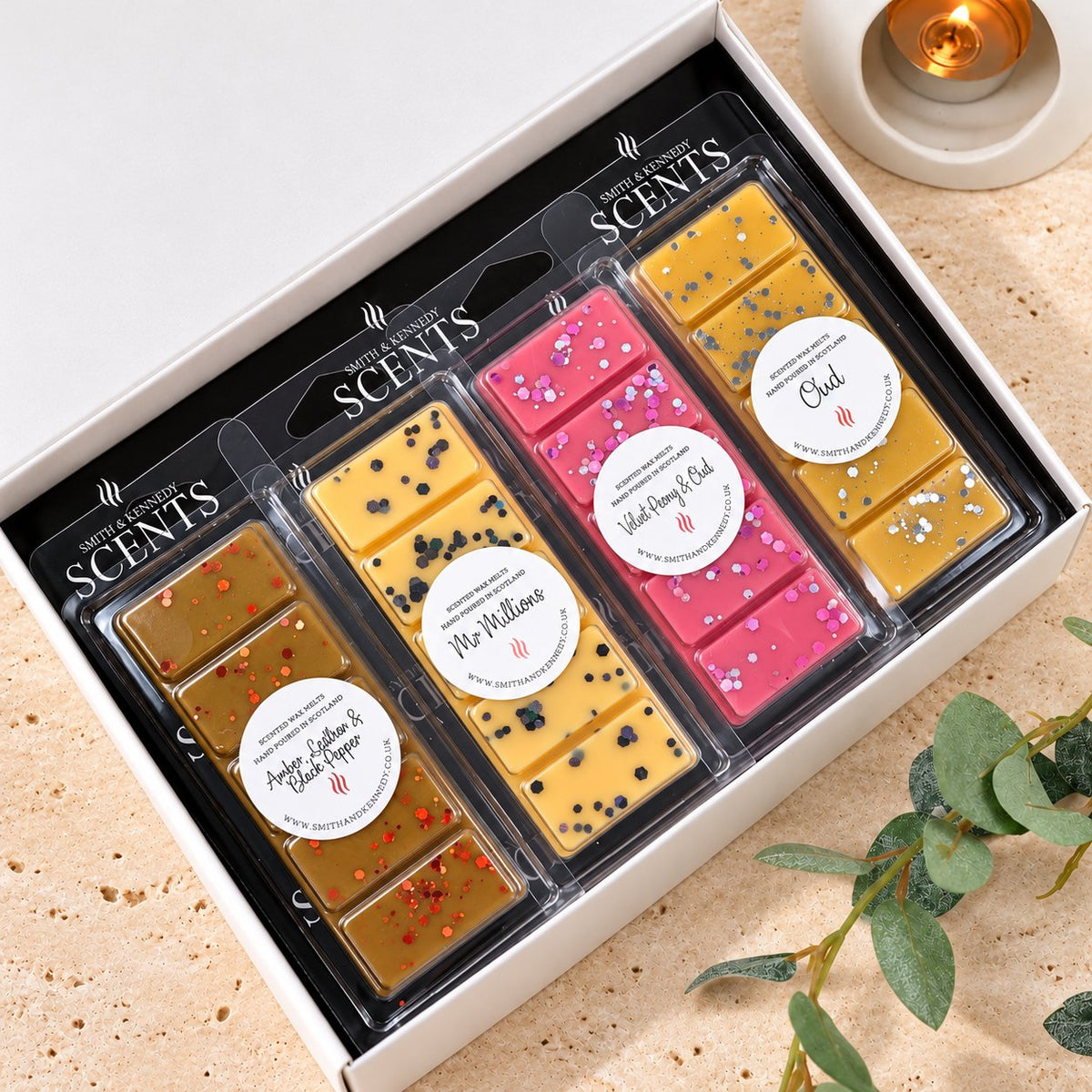 Oud, Wood & Musk Wax Melt Collection by Smith & Kennedy Scents: Amber, Leather & Black Pepper, Mr Millions, Velvet Peony & Oud and Oud snap bars in a white gift box.