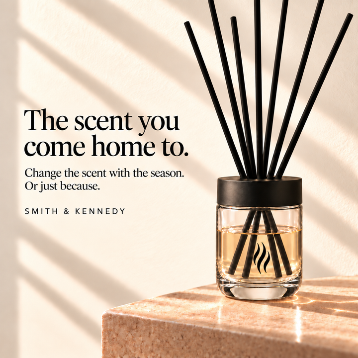 The scent you come home to. Seven black fibre reeds in the reusable SKS diffuser glass against a pale sunlit wall.