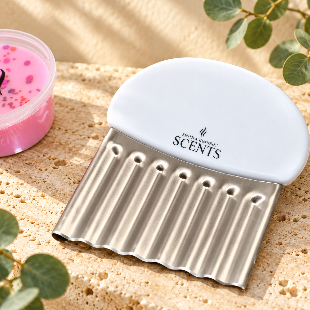 Close-up of the Smith & Kennedy Scents wax melt cutter showing its branded white handle and corrugated silver blade.